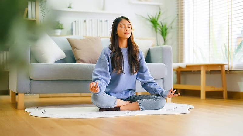 A woman practices meditation, a healthy coping skill that can be developed through life skills for addiction recovery.